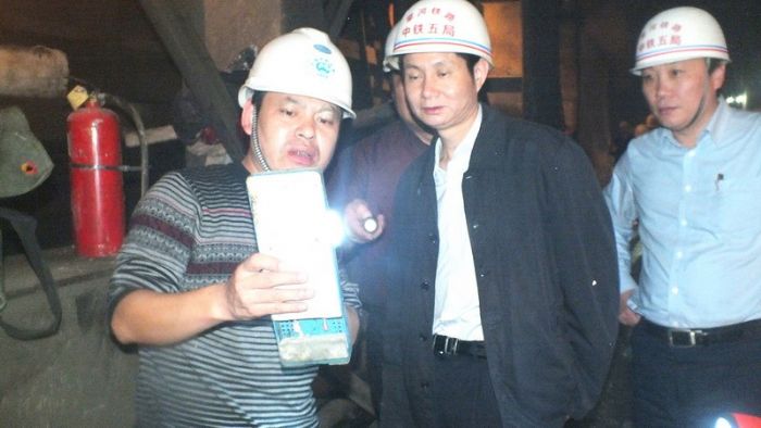 张回家(中)、马江黔(右一)在太阳寨隧道现场察看洞内温度。 何志平 摄<br />